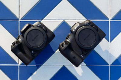 The EOS R7 and EOS R10 on a surface tiled in a bright blue and white chevron pattern